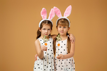 happy cute little child girls with pink bunny ears holding painted Easter eggs on studio yellow background. Easter day