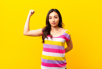 young latin pretty woman feeling serious, strong and rebellious, raising fist up, protesting or...