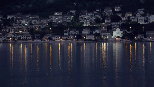 Сity light reflections at the water of Kotor Bay by night. Montenegro