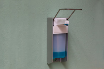 dispenser with a bottle of medical disinfectant hanging on a wall
