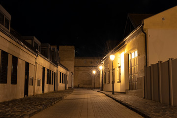 European common night old city street paved road for walking in outdoor lantern yellow light illumination without people