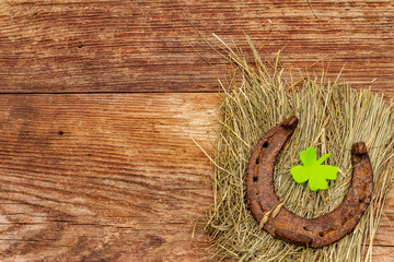 Cast iron metal horse horseshoes with felt clove leaf on hay. Good luck symbol, St.Patrick's Day...