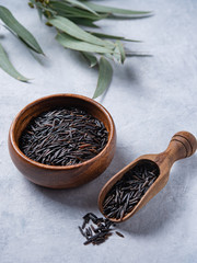 black rice in wood  bowl with spoon  on a light gray background