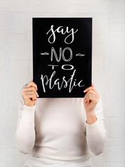 Woman keeping a small chalkboard with SAY NO TO PLASTIC lettering