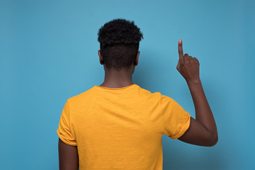 Back view of pointing up blackman. gesticulating showing on copyspace.