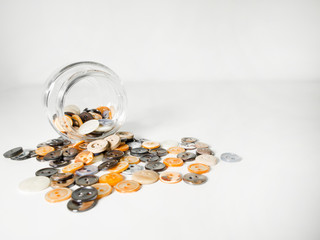 Glass jar full of clothing green, gray and black buttons on white background