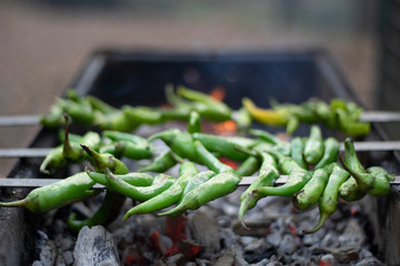 Green peppers with bottles on the grill. The embers grilled in charcoal under it is very hot. Closeup.