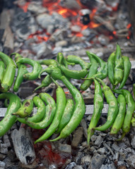 Green peppers with bottles on the grill. The embers grilled in charcoal under it is very hot. Closeup.