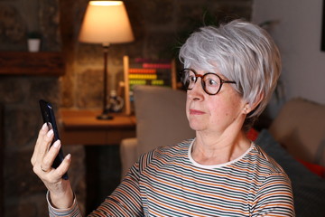 Surprised looking senior woman using cellphone