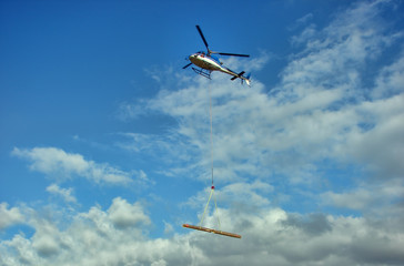 Helicopter transports a wood beam