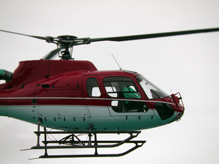 Red helicopter flying in fog