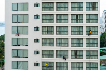 Fototapeta na wymiar Asian industrial worker cleaning windows of a modern building.