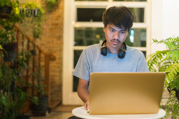 Young man using laptop listening to music on headphone