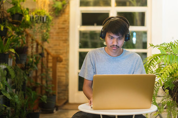 Young man using laptop listening to music on headphone