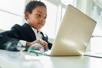 African child as a manager works on the laptop