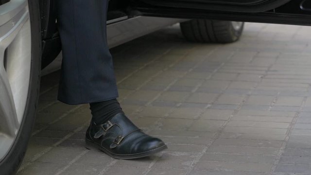 The businessman gets out of the car black legs closeup man slow motion