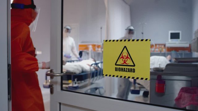 Doctor in protective suit visits patients in biohazard room