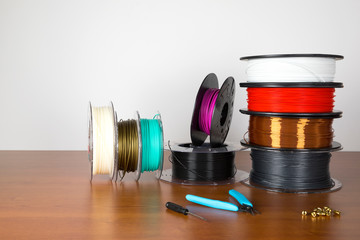 3D printing filament reels and tools for 3d print isolated over white and wooden background