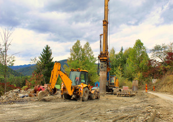 Machinery drilling and backhoe on construction site