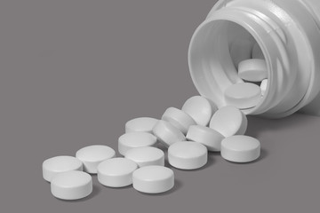 Overturned jar with round pills on gray background