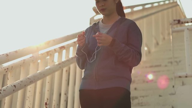 Young women puts the earphones on before run workout standing  sport stadium.