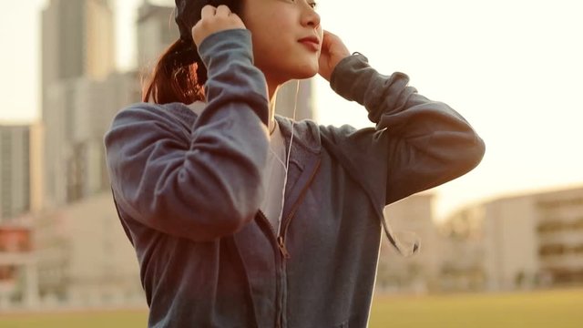 Young women puts the earphones on before run workout standing  sport stadium.