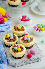 Easter mini brownie cheesecake Bird's Nest with chocolate and candy eggs. Easter dessert. Funny food idea for children. Vertical orientation. Selective focus
