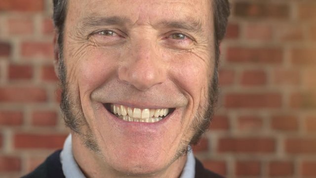 Portrait slow motion of happy handsome attractive mature man with a hipster beard and sideburns standing outside looking at camera. Businessman smiling and laughing. Enjoying life.