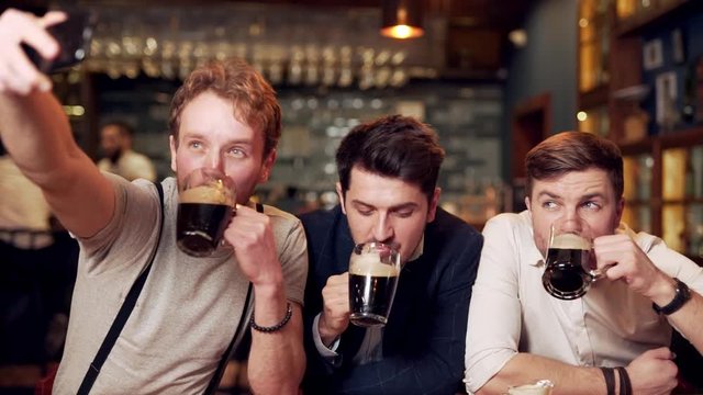 men take selfies with beer at bar