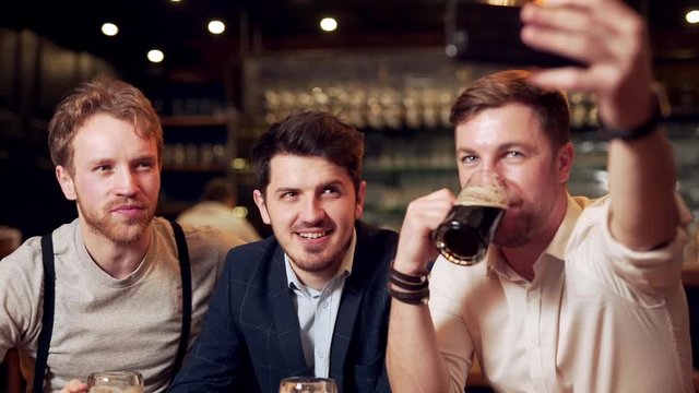 pretty men make selfies with dark beer at the bar