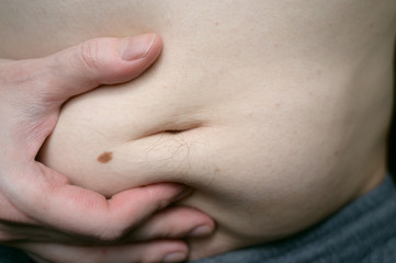 Young man touching his fat belly.