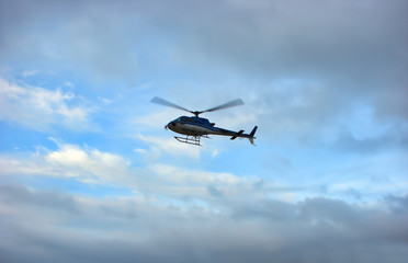 Blue helicopter in cloudy sky