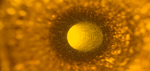 Interior of orange abstract pipe with light coming from circular hole at the end. Abstract science...