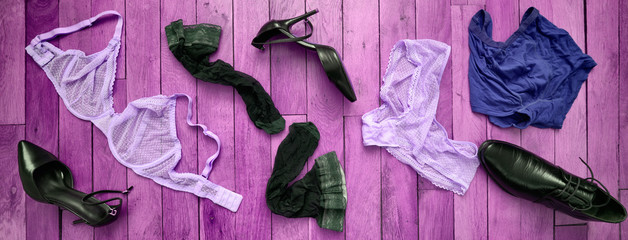 Top view at wooden purple painted floor with scattered underwear, stockings and shoes left by woman and man having date. Passionate sex relation high resolution banner concept.