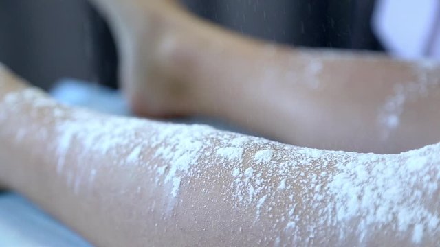 Master shugaring to apply body powder. Natural procedure background