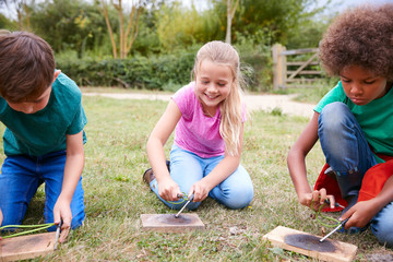 Group Of Children On Outdoor Camping Trip Learning How To Make Fire