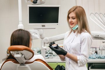 the doctor conducts a dialogue with the patient, and shows a model of the jaw from plaster