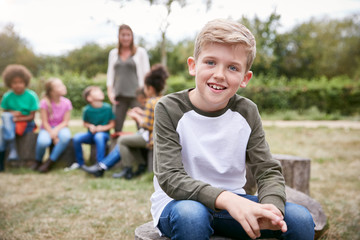 Portrait Of Boy On Outdoor Activity Camping Trip Sitting Around Camp Fire With Friends