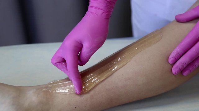 azulene depilation. wax hair removal, shugaring. concept of smooth skin without hair. azulene color. the master puts azulene on the girls legs
