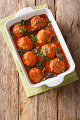Baked meatballs with wild mushrooms in tomato sauce close-up in a pan. Vertical top view