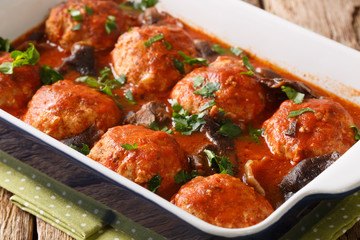 Italian meatballs with wild mushrooms in a spicy tomato sauce close-up in a pan. horizontal