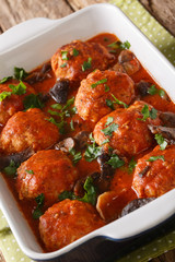 Cooked meatballs with mushrooms in tomato sauce close-up in a pan. vertical