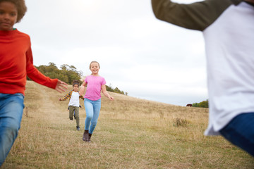 Front View Of Group Of Children On Outdoor Activity Camping Trip Running Down Hill