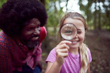 Girl With Male Team Leader At Outdoor Activity Camp Studying Forest Nature With Magnifying Glass