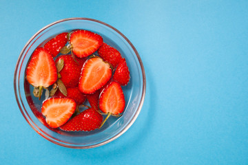 Sliced strawberries in water on top. Strawberries in a plate.