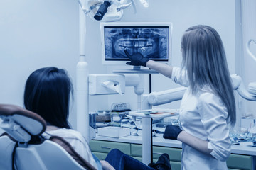 girl dentist shows on roentgen to patient