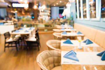 Row of empty dinner tables decorated with tablecloths and napkins in cozy restaurant