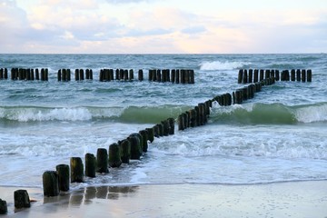 Fototapeta premium Waves crashing on the breakwater on a sunny day. Baltic Sea coast, Dziwnowek, Poland