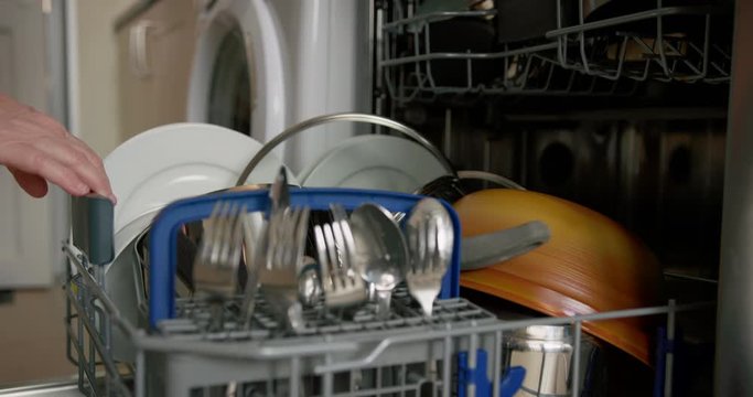 Mature woman emptying the clean dishwasher