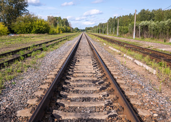 Old railway tracks without wires. Rails converge at one point on the horizon